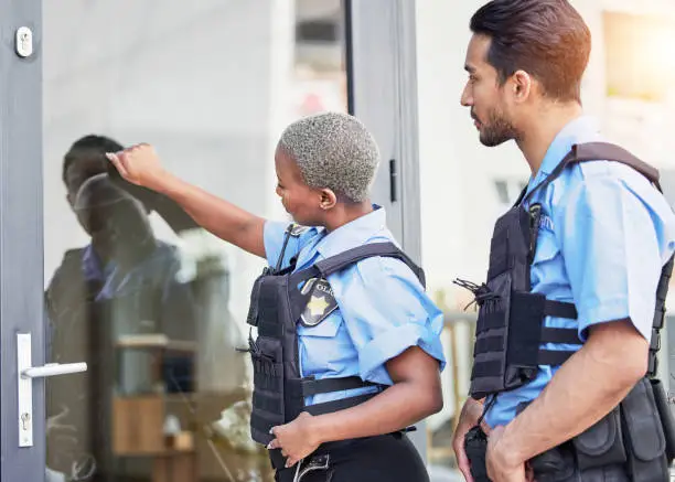 Two security officers in blue uniforms, one pointing at a glass door while the other observes, symbolizing vigilance and protection in legal matters.
