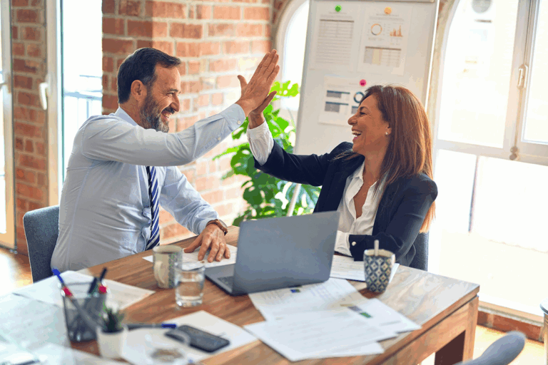 Two smiling professionals giving a high-five in a modern office setting, symbolizing collaboration and success in child custody legal services.
